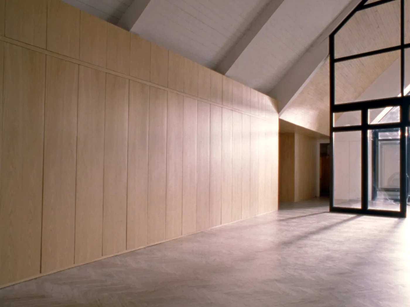 Mur de rangements en chêne sur mesure sous rampant, avec verrière d’atelier en acier noir