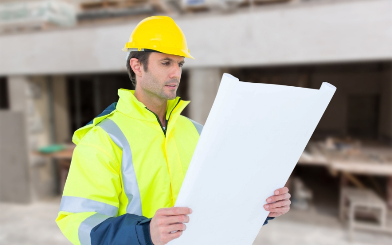 Chef de travaux TCE analysant un plan pour coordonner un chantier