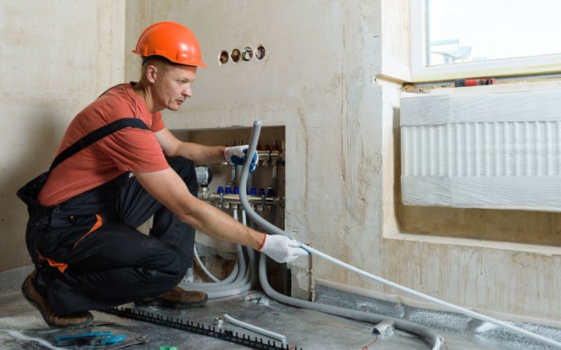 Plombier installant des canalisations d’eau dans une maison en construction à Paris